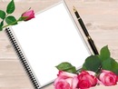 cuaderno, pluma y rosas rosadas.
