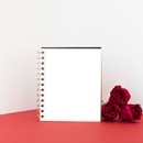 cuaderno y rosas rojas, sobre mesa.